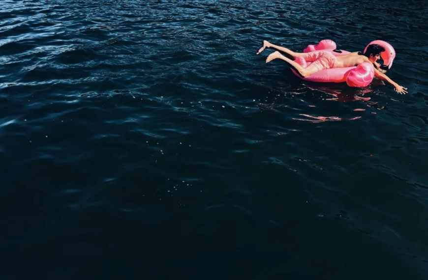 A young man on a pink flamingo float, just going with the flow.