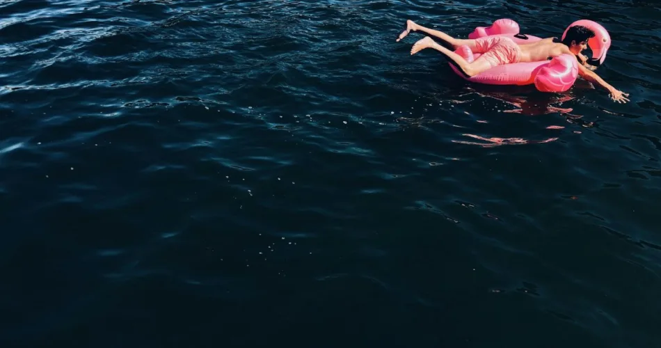 A young man on a pink flamingo float, just going with the flow.